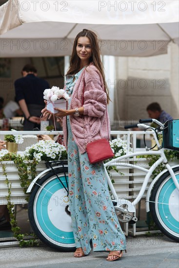 Caucasian woman carrying gift box near bicycle