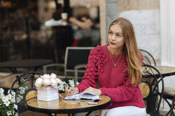 Caucasian woman sitting at table writing in journal