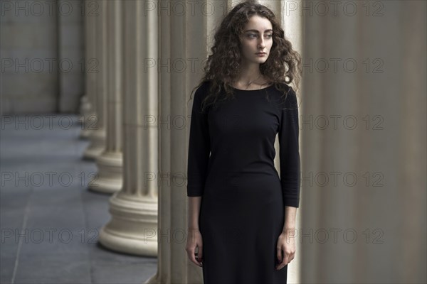 Serious Caucasian woman standing near pillars