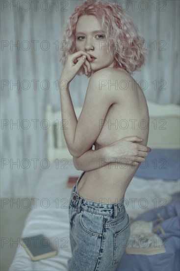 Portrait of pensive topless Caucasian woman in bedroom