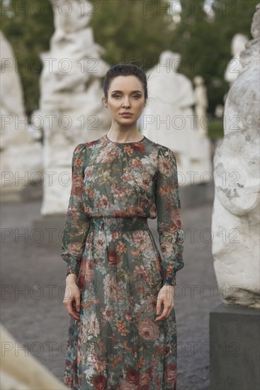 Portrait of confident Caucasian woman standing near statues