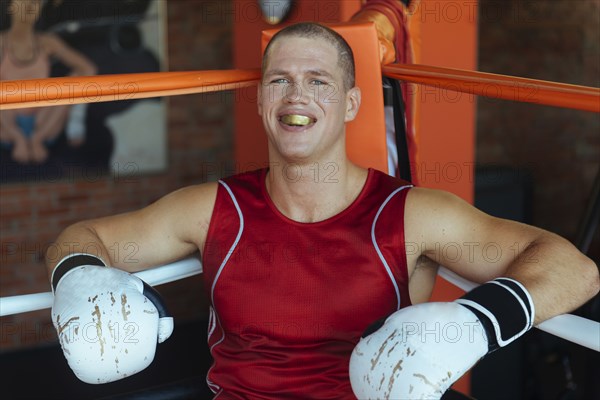 Portrait of Caucasian boxer sitting in corner of boxing ring