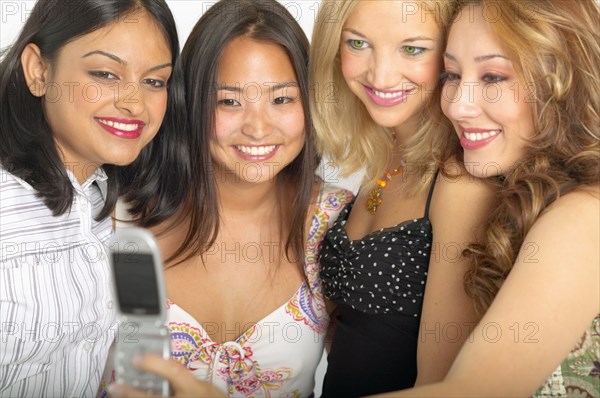 Female friends taking photograph with cell phone