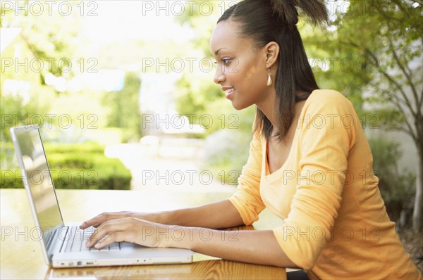 Profile of teenage girl typing on laptop