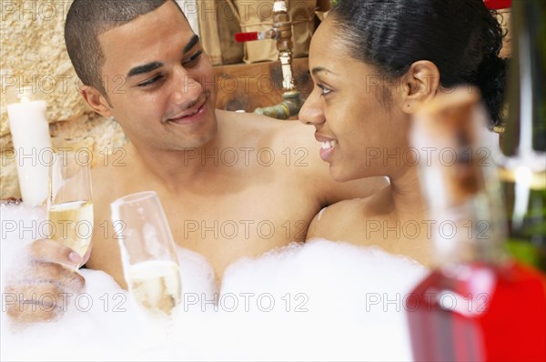 Couple drinking champagne in bubble bath