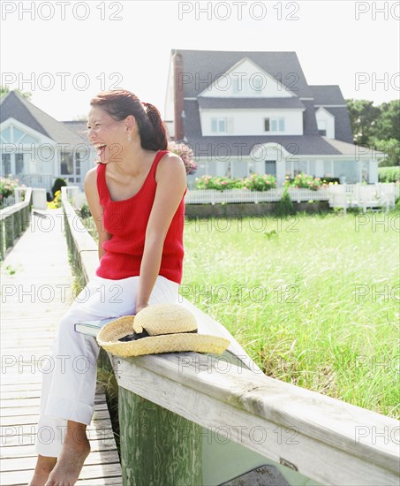 Young woman laughing while sitting on railing