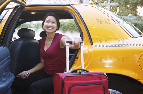 Young woman with suitcase inside a cab