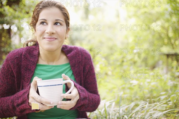 Young woman holding a cup in garden