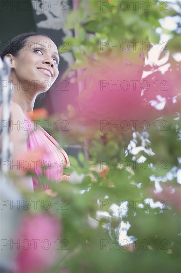 Young woman standing behind plants