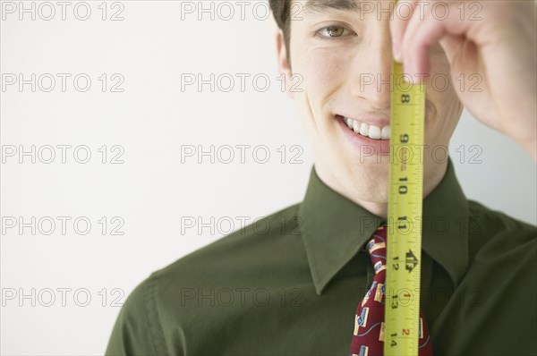Close-up of a businessman holding a ruler in front of his face