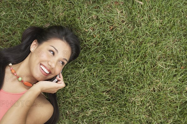 Woman lying on grass talking on mobile phone