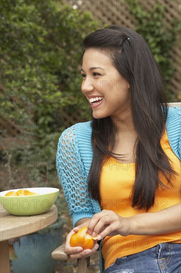 Young woman peeling an orange