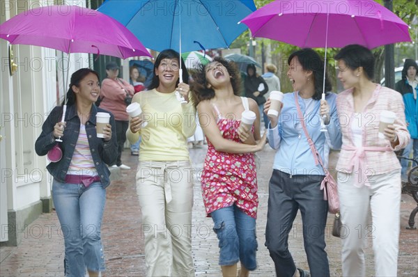 Group of women walking and laughing with umbrellas