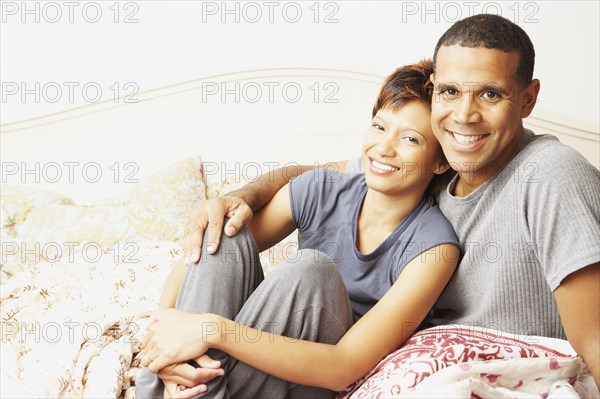 Young couple smiling for the camera in bed