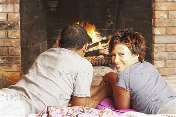 Young couple relaxing in front of a fire