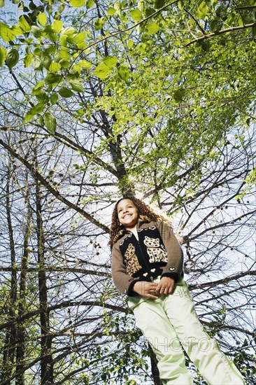 Low angle view of young girl under tree