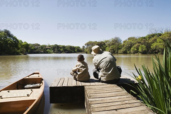 Father and son sitting on dock