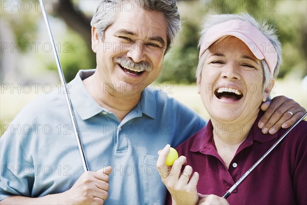 Middle-aged couple laughing with golf clubs