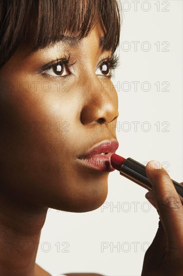 Close up of African woman applying lipstick