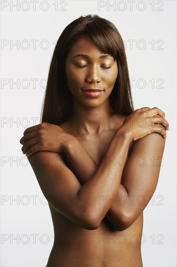 Nude African woman covering breasts