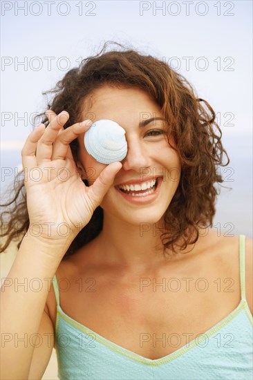 Woman holding seashell over eye