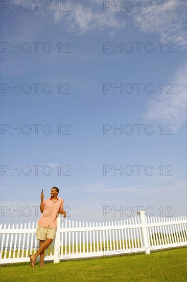 Hispanic man leaning on fence