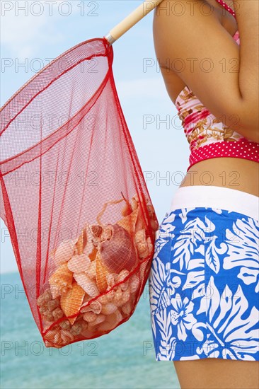 Woman carrying net full of seashells