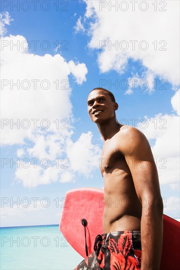 African man holding body board on beach