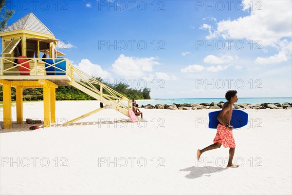 African man running with body board on beach