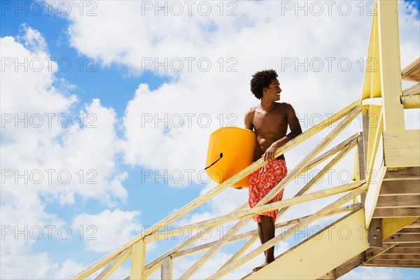 African man holding body board on lifeguard hut ramp