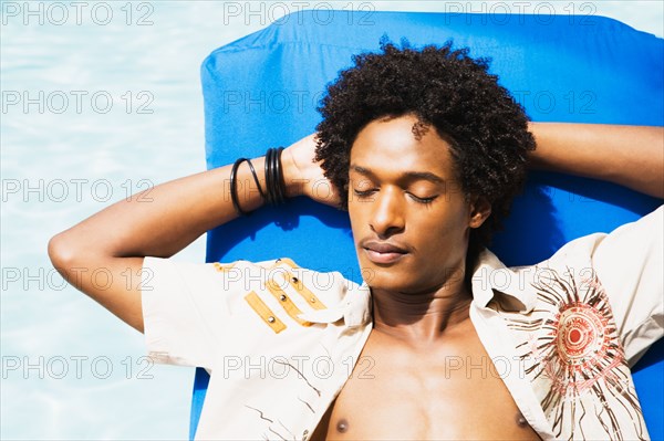 African man laying in sun with eyes closed