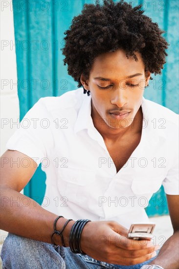 African man looking down at cell phone
