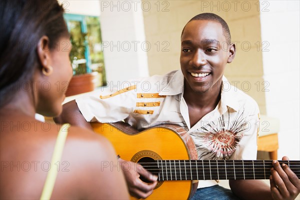 African man playing guitar for woman