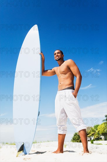 African man holding surfboard on beach