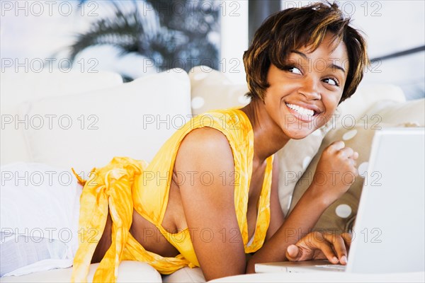 African woman using laptop on sofa
