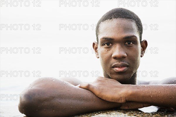 African man leaning on edge of swimming pool