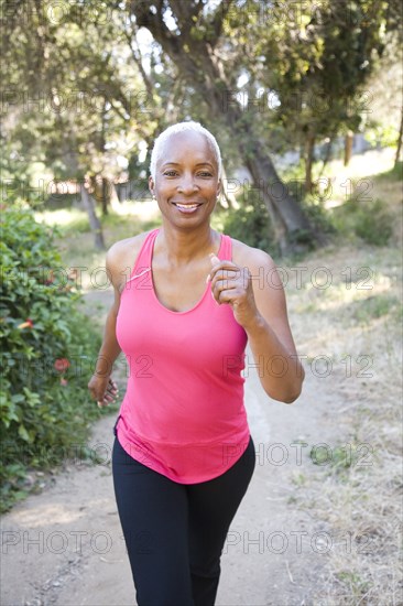 Mixed race woman running on wooded path