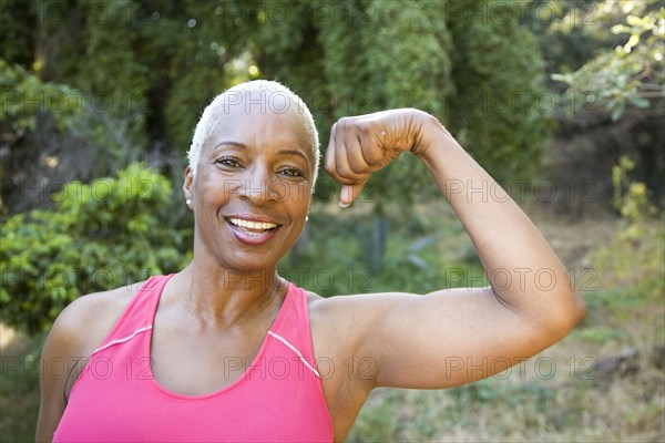 Mixed race woman flexing muscles outdoors