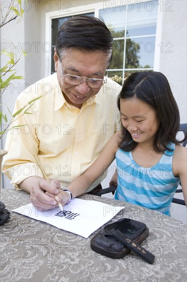 Chinese grandfather teaching granddaughter calligraphy