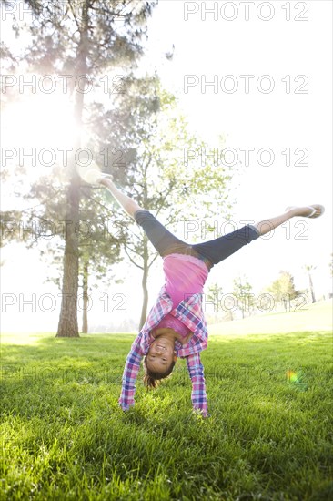 Chinese girl doing cartwheel in grass