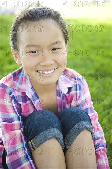 Smiling Chinese girl sitting in grass