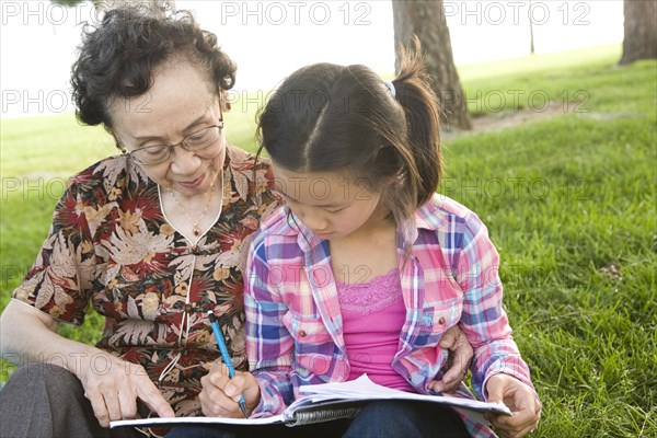 Chinese grandmother watching granddaughter doing homework