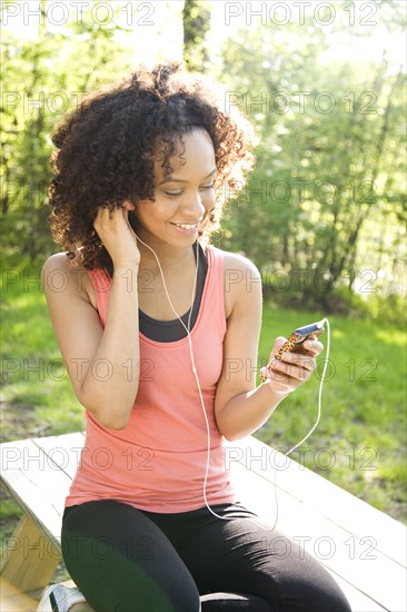 Hispanic woman in sportswear listening to mp3 player