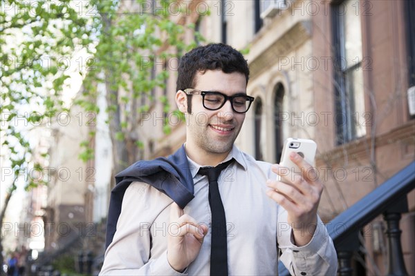 Hispanic businessman using cell phone outside