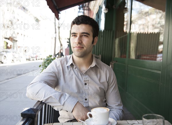 Hispanic man sitting at sidewalk cafe