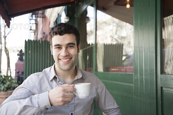 Hispanic man sitting at sidewalk cafe