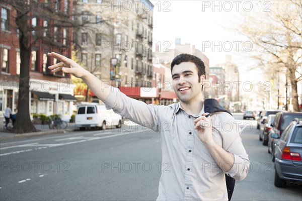 Hispanic man hailing taxi on city street