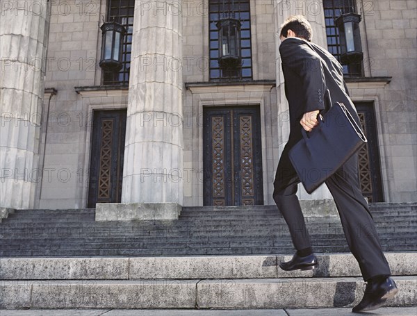 Businessman running up stone stairs