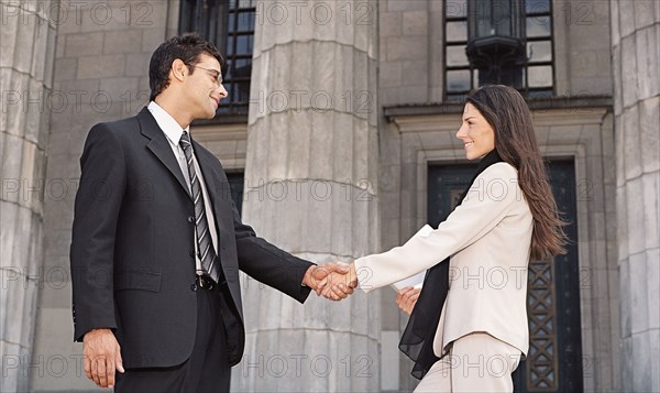 Businesspeople shaking hands in front of building