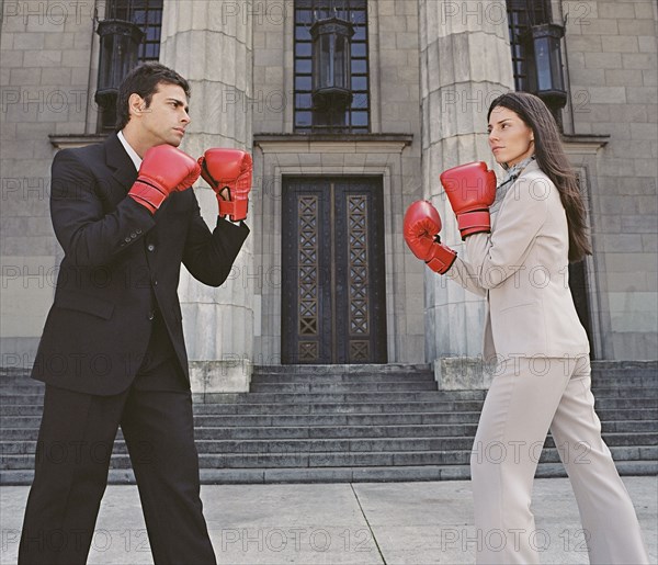 Businessman and businesswoman sparring in front of building